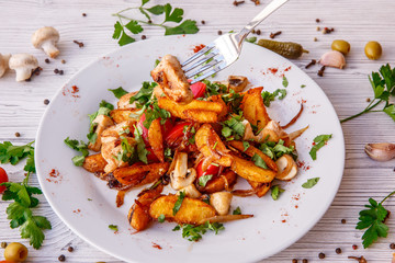 fried potatoes with mushrooms meat onions on a plate wooden white background