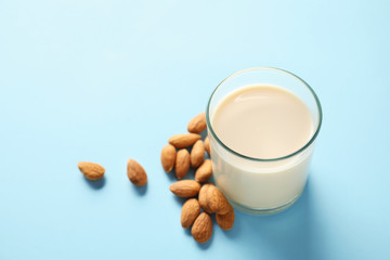 Glass of tasty almond milk on color background