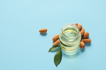 Jar of almond oil on color background