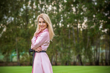 Obraz na płótnie Canvas Romatic blonde hair woman in pretty pink elegant dress at park