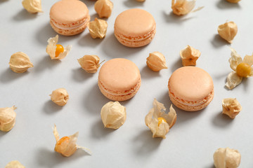 Tasty macarons with physalis on grey background