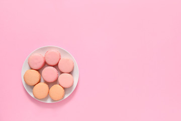 Plate with tasty macarons on color background