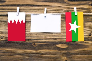 Hanging flags of Bahrain and Myanmar attached to rope with clothes pins with copy space on white...