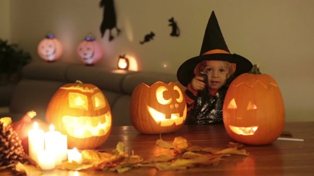 Cute child, playing with carved pumpkin at home on Halloween, making magic potion