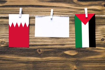 Hanging flags of Bahrain and Palestine attached to rope with clothes pins with copy space on white...