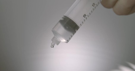 Hand dripping liquid from syringe onto a wet surface - Powered by Adobe