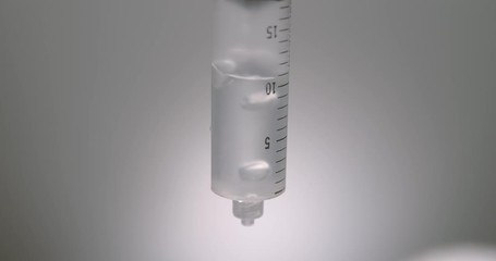 Hand dripping liquid from syringe onto a wet surface - Powered by Adobe