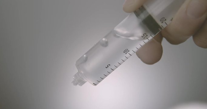 Hand dripping liquid from syringe onto a wet surface