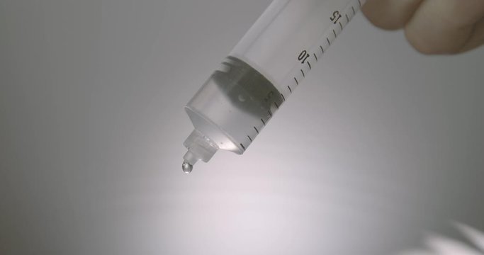 Hand dripping liquid from syringe onto a wet surface