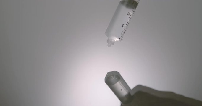Hand dripping liquid from syringe onto a wet surface