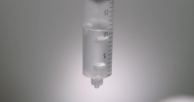 Hand dripping liquid from syringe onto a wet surface