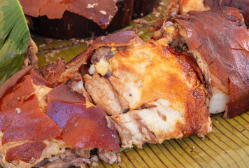 Roasted meat on banana leaf. Outdoor eatery with grilled pork photo. Whole pig barbecue. Traditional filipino dish.