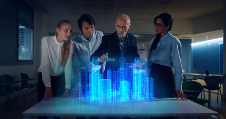 A group of modern designers are using a futuristic sophisticated technology screen with augmented...