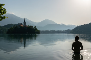 Fototapeta premium Silhouette of an European man bathing in lake Bled