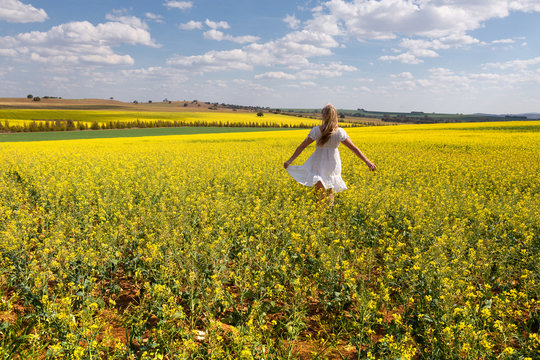 Country girl frollicking in fields of golden canola