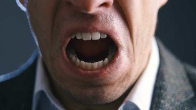 Close-up mouth of angry annoyed boss man screaming at camera. Businessman aggressively shouts experiencing stress at work.