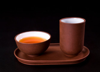 Asian tea ceremony. Clay tea cups and tea drink on a black background.