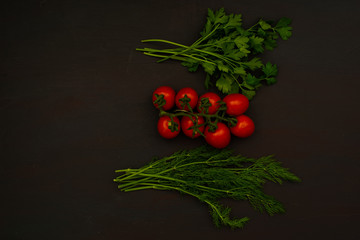 Organic farming cherry pamidor with parsley and dill on black kitchen table