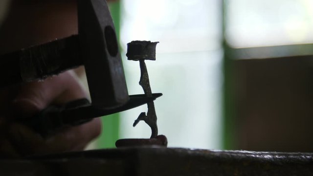Male hands hitting and making a beautiful rose on an anvil in a workshop
