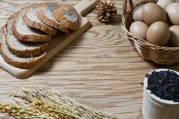 bread loaf and wheat ears and sack on wooden background.