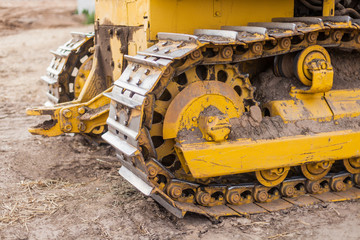 Fototapeta na wymiar Yellow Tractor on crawler track. Close-up of crawler bulldozer truck. Earthmoving heavy machinery
