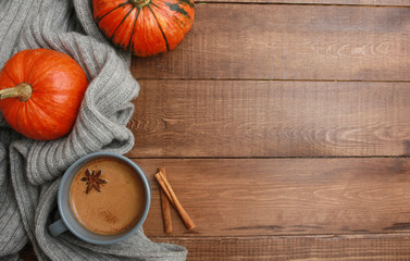 Grey cup of coffee with milk and spices, plaid, orange pumpkins on dark brown wooden table. Autumn drink concept. Fall, pumpkin spicy latte, thanksgiving, top, copy space