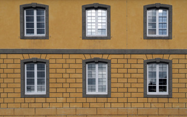 Gelbe historische Hausfassade mit sechs Holzfenstern