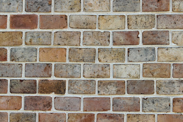 Texture of an old damaged decorative brick wall made of bricks of different colors