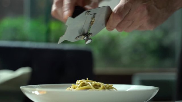 Slow motion of chef slice black truffle to pasta