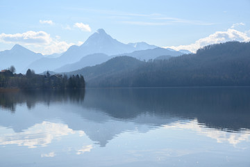 weissensee, idyllic lake in dusty morning light front of the blue mountains of the bavarian alps...