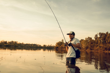 Man fishing  in the lake at sunset.