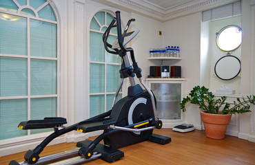 Fitness Center Gym Room onboard luxury cruise ship sailing yacht with portholes and free weights,...