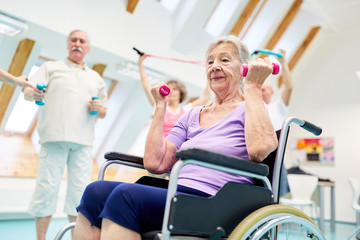 Seniorin im Rollstuhl trainiert Fitness mit Hanteln