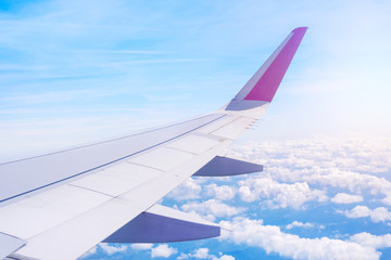 Obraz premium Airplane wing with sun and clouds in background.