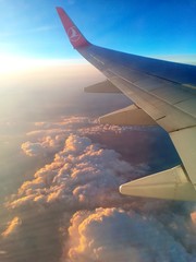 Obraz premium wing of an airplane flying above the clouds