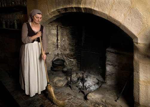 Woman cleaning at medieval fireplace