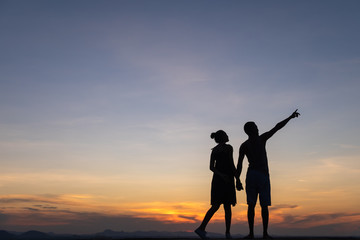 Silhouettes of happy young couple against the sunset sky.