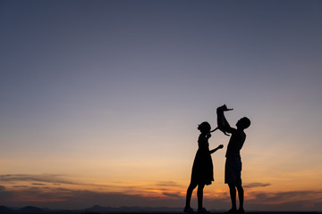 Fototapeta premium Silhouettes of happy young couple against the sunset sky,cat