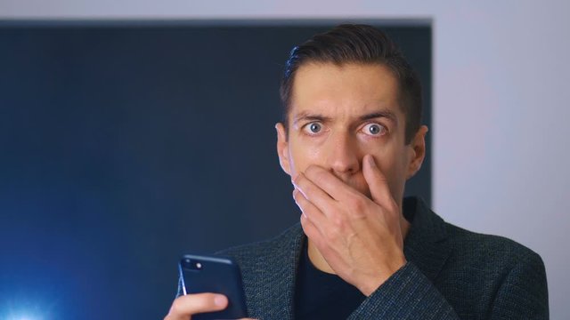 Portrait of shocked and disgusted man. Confused man saw an unpleasant message on a smartphone. He is worried about seeing. Close-up.