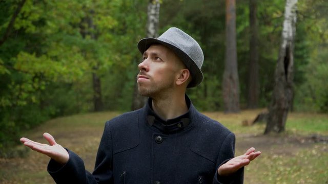 The reaction of the man in the hat and coat when the rain suddenly began.