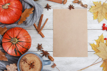 Grey spicy coffee cup,  plaid or scarf, yellow leaves, pumpkins, blank paper on white wooden table. Autumn drink concept. Fall, spicy latte, thanksgiving, top, copy space