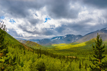 Fototapeta na wymiar Mountain forest landscape under stormy sky with clouds. Khibiny mountains above the Arctic circle, Kola peninsula, Murmansk region, Russia