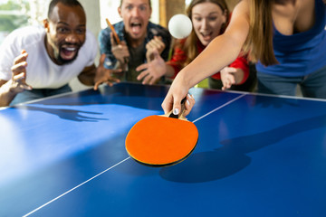 Young people playing table tennis in workplace, having fun. Friends in casual clothes play ping...
