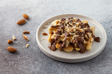 Belgian waffle with chocolate and almonds on a white plate