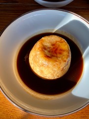 Ox and kidney pudding with gravy sauce on a white plate in strong sunlight at a lunchtime. Delicious traditional british homemade cosine.