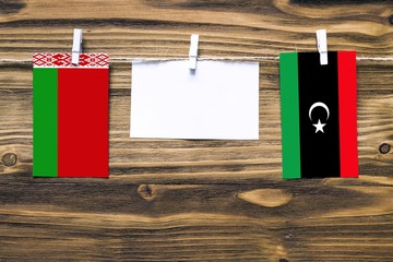 Hanging flags of Belarus and Libya attached to rope with clothes pins with copy space on white note...