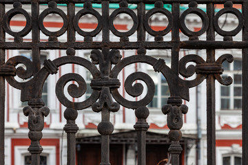 Fragment of an old cast-iron fence with an ornate ornament and traces of corrosion