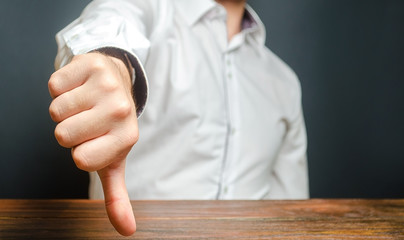A man shows a thumb down. Gesture of disapproval and rejection. Bad assessment, harsh criticism,...