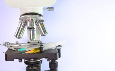 microscope professional with syringes filled with drugs and antibiotics.