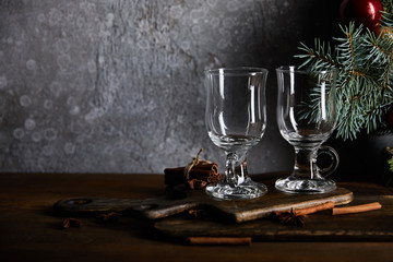 empty cocktail glasses on cutting board near spruce branch on grey textured background